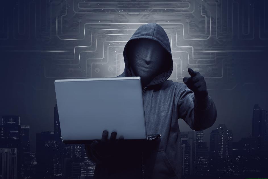 Gestalt mit Kapuze und Laptop in der Hand
